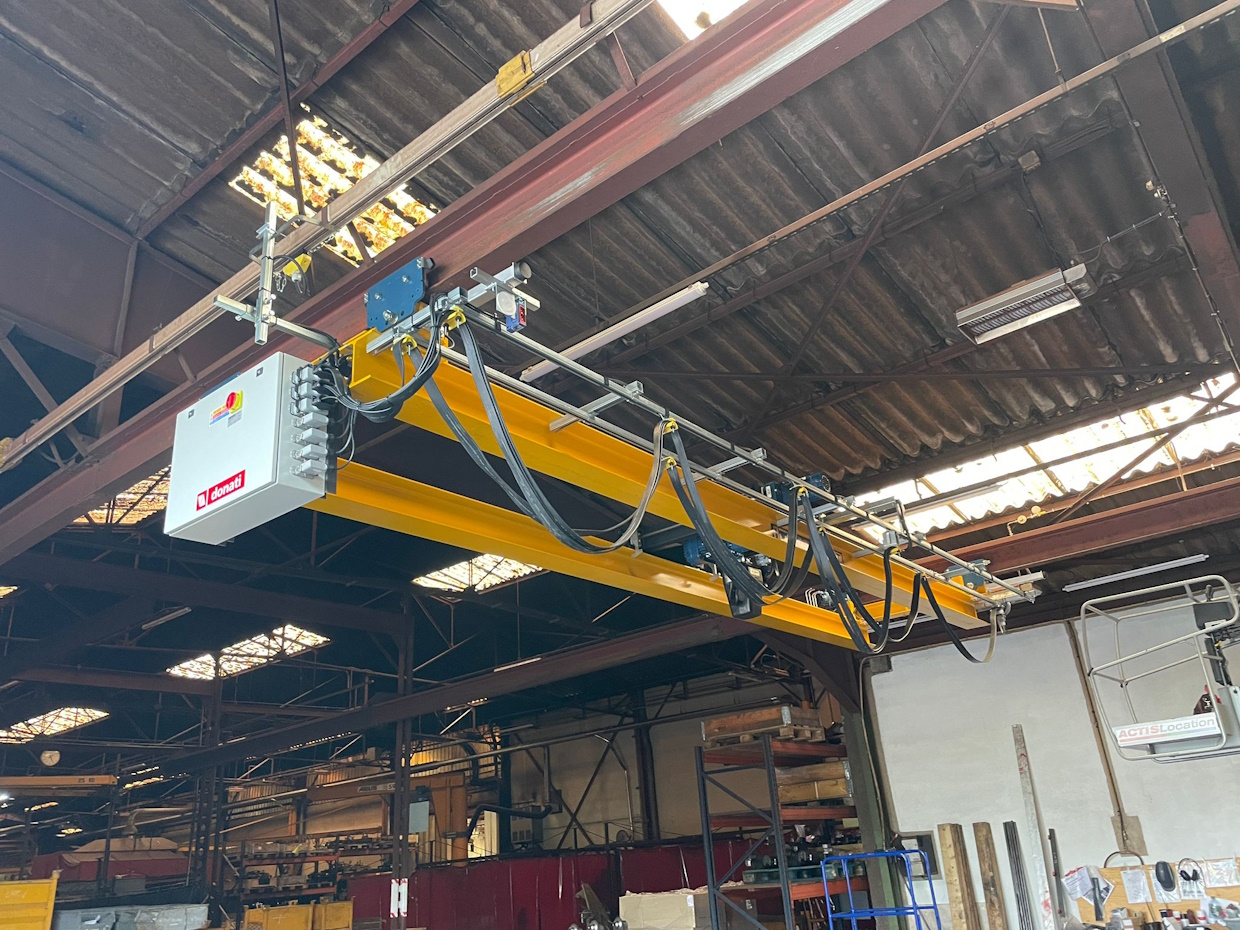 Pont roulant jaune dans un atelier industriel.